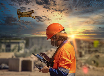 Man working with umbrella against sky during sunset