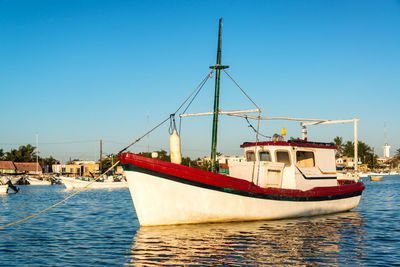 Boat moored in sea against clear blue sky