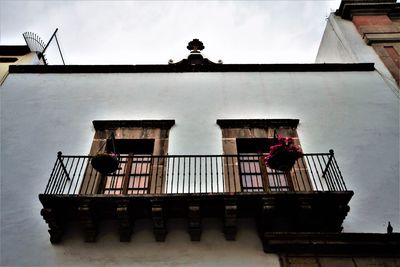 Low angle view of men standing by building against sky