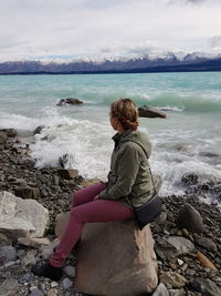 Rear view of man sitting on rock at beach