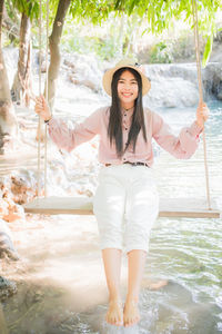 Full length portrait of young woman standing in water