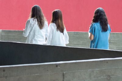 Rear view of two women sitting on railing