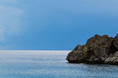 Scenic view of sea and rocks against clear blue sky