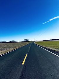 Empty road against clear blue sky