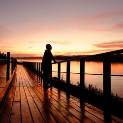 Silhouette man standing on pier against sky during sunset