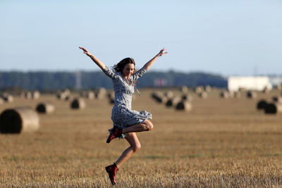 Full length of woman doing yoga on field against sky