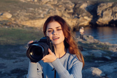 Portrait of smiling woman photographing water