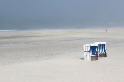 Hooded beach chair on beach against sky