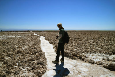 Man standing on beach against clear sky during winter