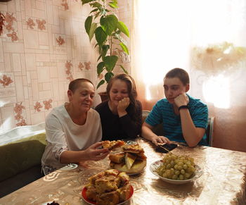 Guests are talking at a table covered with homemade people talk to young people, offer pies.