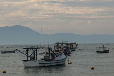 Boats in sea with mountains in background