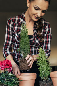 Young woman looking away while sitting on potted plant