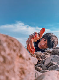 Portrait of boy on rock against sky