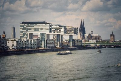 Sea by buildings in city against sky