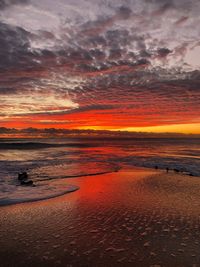 Scenic view of sea against dramatic sky during sunset