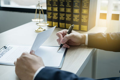 Midsection of man reading book on table