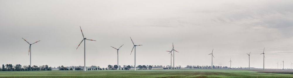 Panoramic view of windmills on field against sky