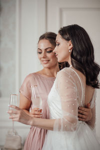 Bridesmaid and bride holding champagne flute