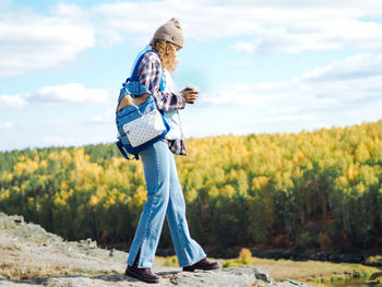 Young curly woman traveller walking at mountain river in autumn