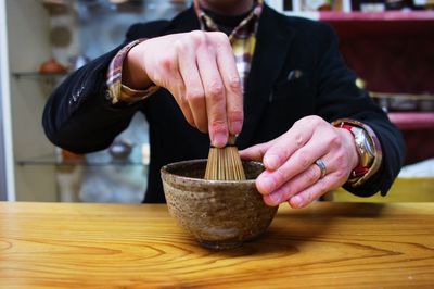 Midsection of man using mortar and pestel at table