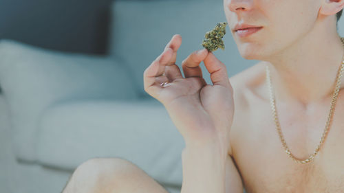 Midsection of shirtless man holding marijuana