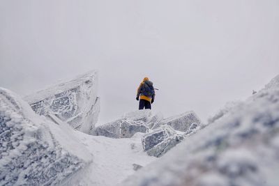 Man skiing on snowcapped mountain against sky