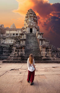 Rear view of woman at temple against sky during sunset