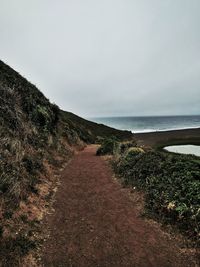 Empty footpath at sea shore against clear sky