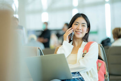 Young woman using phone while sitting at cafe