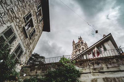 Low angle view of skyscrapers against cloudy sky