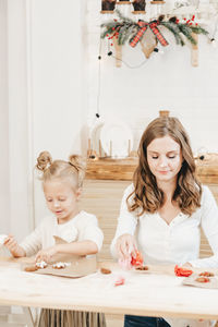 Caucasian mom and daughters are preparing christmas cookies in the kitchen.