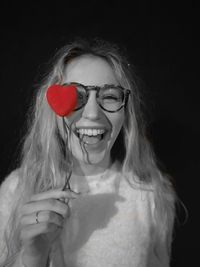 Portrait of young woman against black background