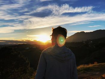 Man looking at mountain against sky during sunset