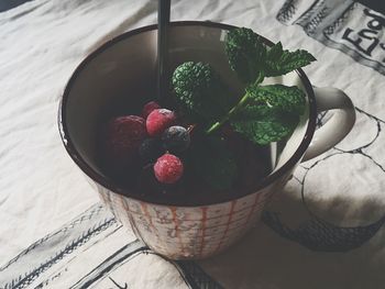 High angle view of mint leaves and berries in cup on table