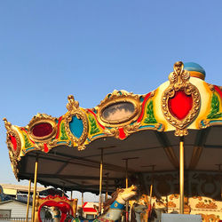 Low angle view of illuminated carousel against clear blue sky