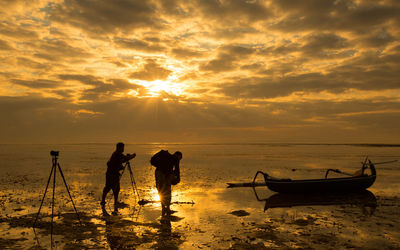 Silhouette of people on boat at sunset