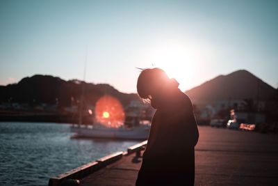 Person standing on pier over lake against sky during sunset