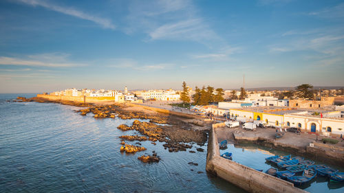 Scenic view of river by buildings against sky during sunset