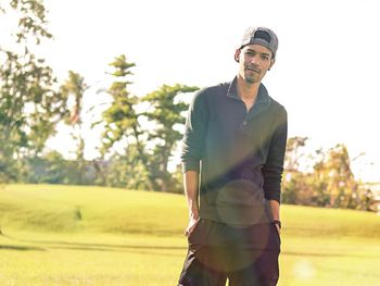 Portrait of young man standing on field during sunny day