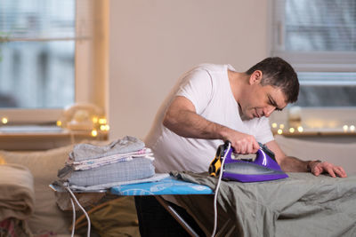 Man ironing clothes at home