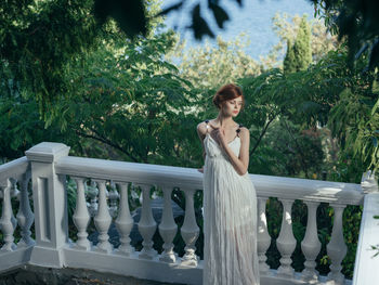 Woman standing by railing against trees