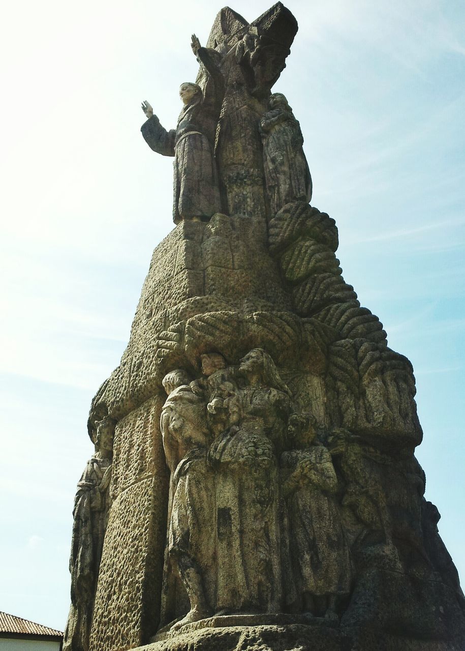 low angle view, statue, sculpture, human representation, art and craft, sky, art, creativity, religion, spirituality, cloud - sky, history, carving - craft product, famous place, outdoors, day, no people, tree