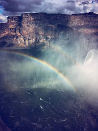 Scenic view of rainbow over mountain against sky