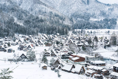 Aerial view of snow covered tree and buildings in city