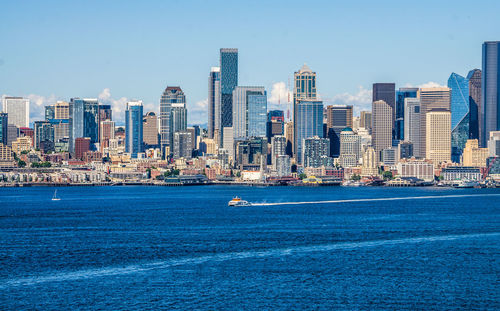 Sea by modern buildings against clear sky