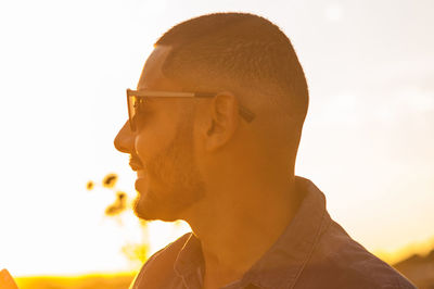 Close-up of man standing by railing during sunset