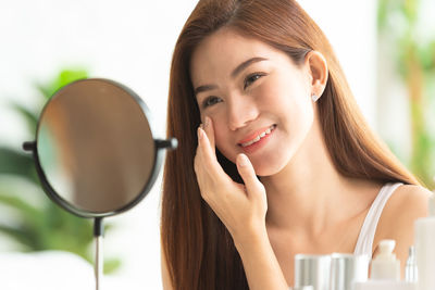 Portrait of a smiling young woman holding camera