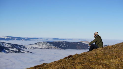 Man standing on snowcapped mountain against clear sky