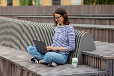 Young woman using phone while sitting on chair