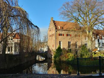 Arch bridge over river amidst buildings against clear sky